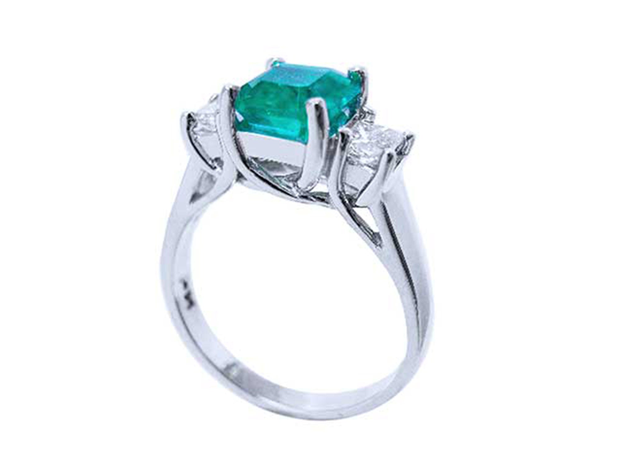 An emerald engagement ring with princess cut side diamonds on its half side profile, displaying the top and gallery. 