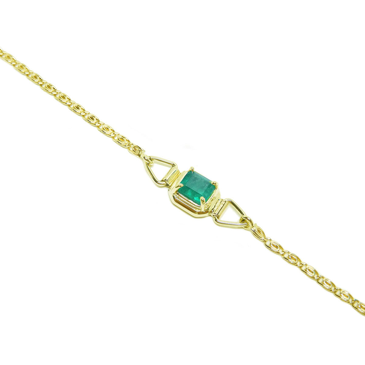 The lateral view of a gold bracelet with a Muzo colombian emerald on a white background.
