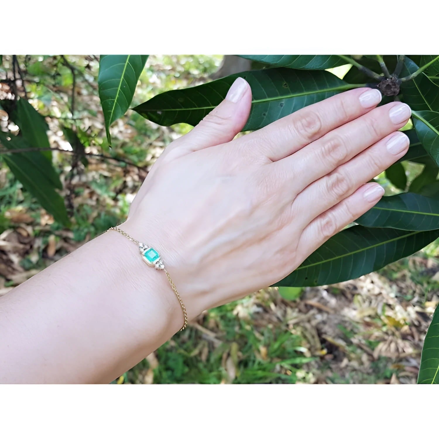 Women's 14k yellow gold bracelet with a 0.85 ct emerald and six natural diamonds on a wrist.