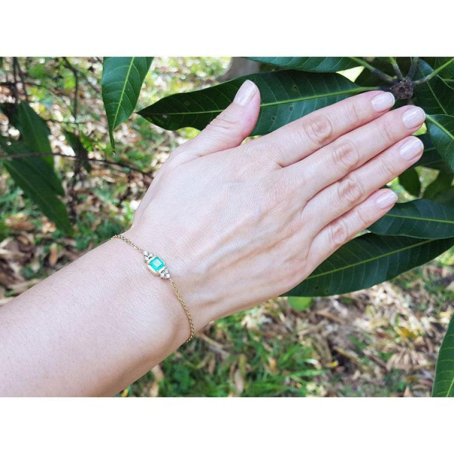 Women's 14k yellow gold bracelet with a 0.85 ct emerald and six natural diamonds on a wrist.