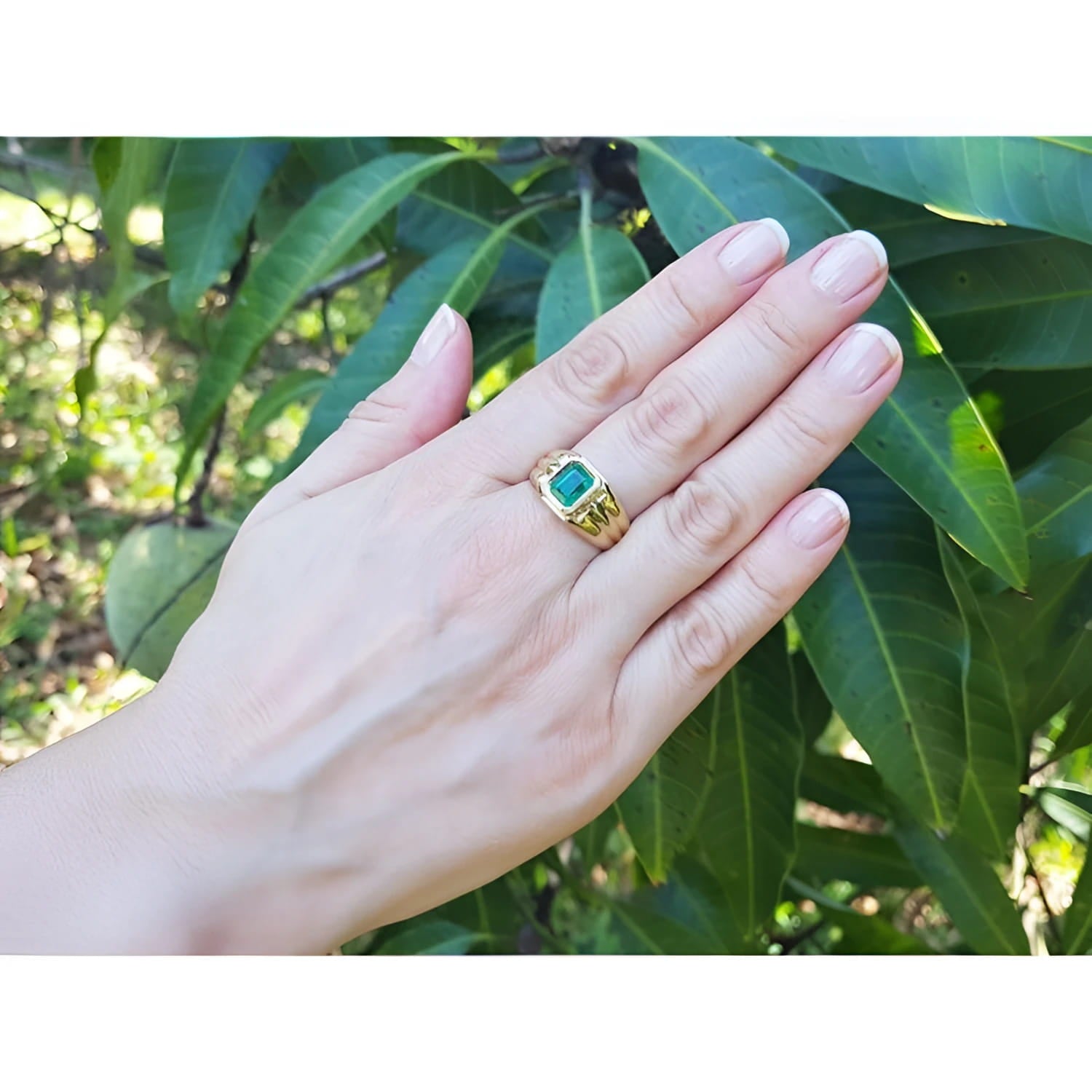 Men's 1.57 ct deep green Colombian emerald solitaire ring, bezel set in 14K yellow gold on a hand.