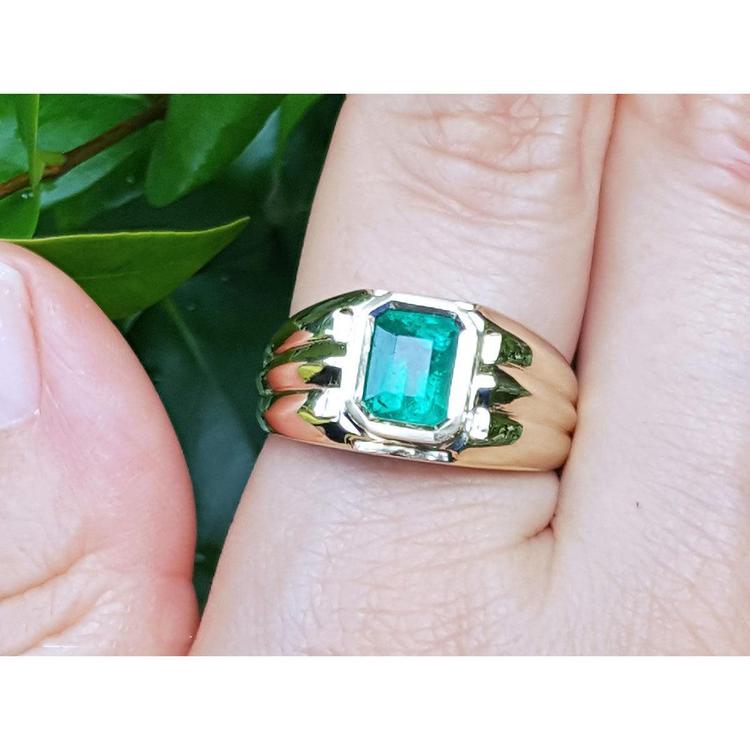 14k gold solitaire ring for men with a natural colombian emerald bezel set worn on a hand.