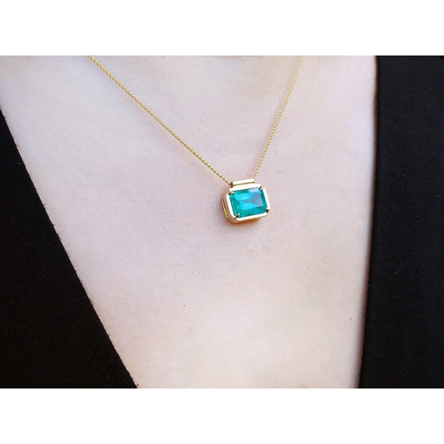 Natural Muzo Colombian emerald solitaire necklace in 18K yellow gold, east-west orientation.
