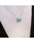 Natural Muzo Colombian emerald solitaire necklace in 18K yellow gold, east-west orientation.