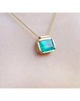 18K yellow gold necklace with a vibrant deep green emerald solitaire in an east-west setting.