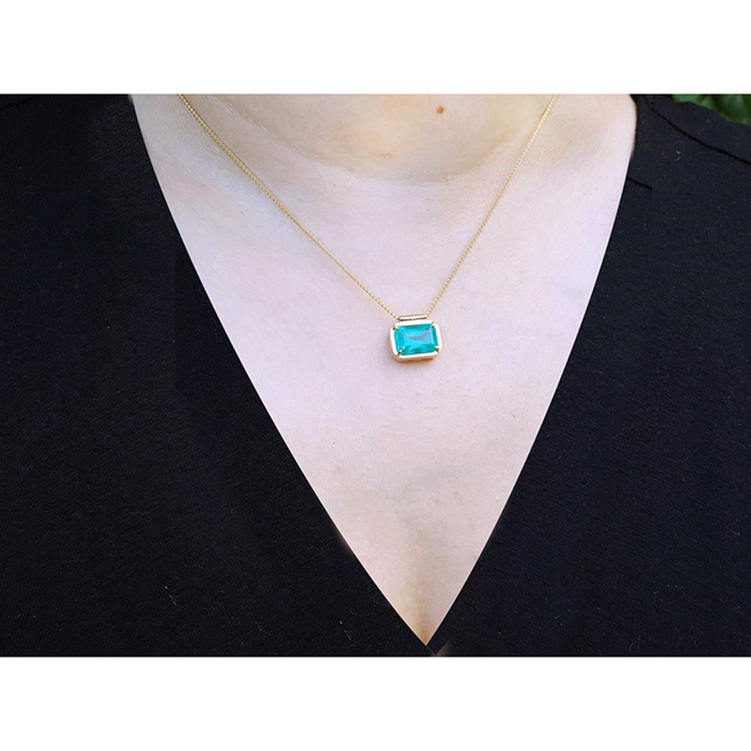 18K yellow gold necklace with a vibrant deep green emerald solitaire in an east-west setting.