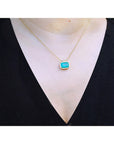 18K yellow gold necklace with a vibrant deep green emerald solitaire in an east-west setting.