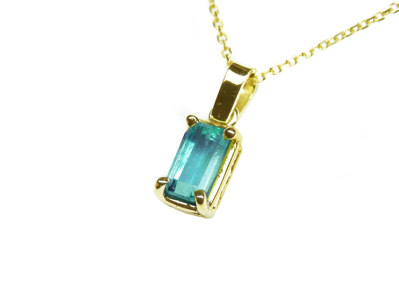 A yellow gold emerald solitaire pendant showing the topside and gallery profile.