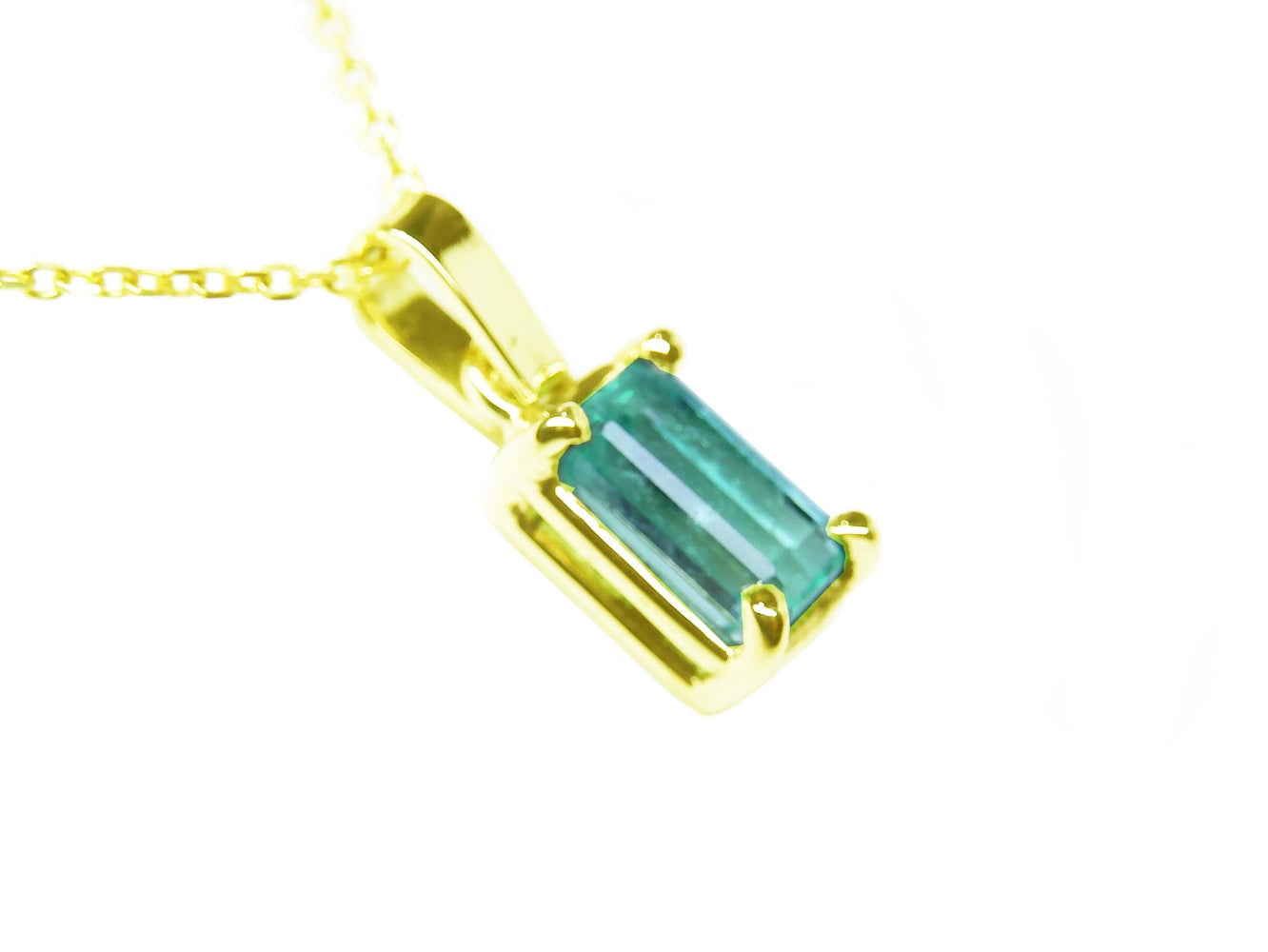 A yellow gold emerald solitaire pendant showing its top and side gallery profile.