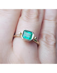 An emerald solitaire ring crafted in 14k yellow gold on a finger