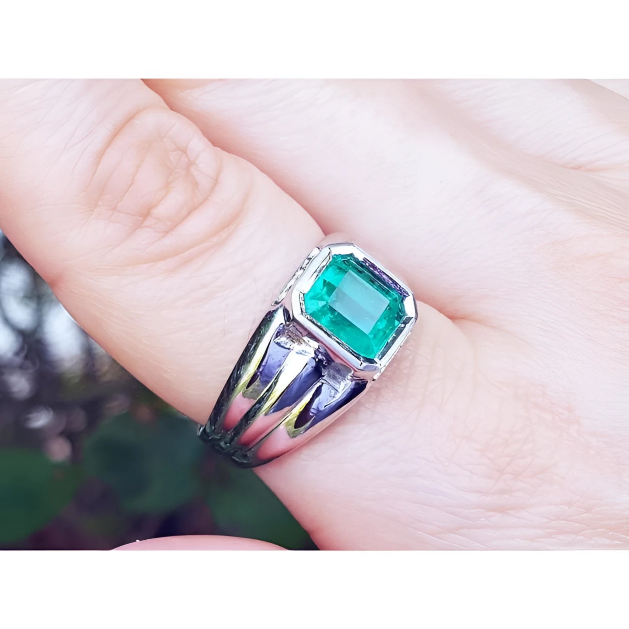 This 18k white gold men's natural colombian emerald solitaire ring is a bezel set tyle worn on a finger.