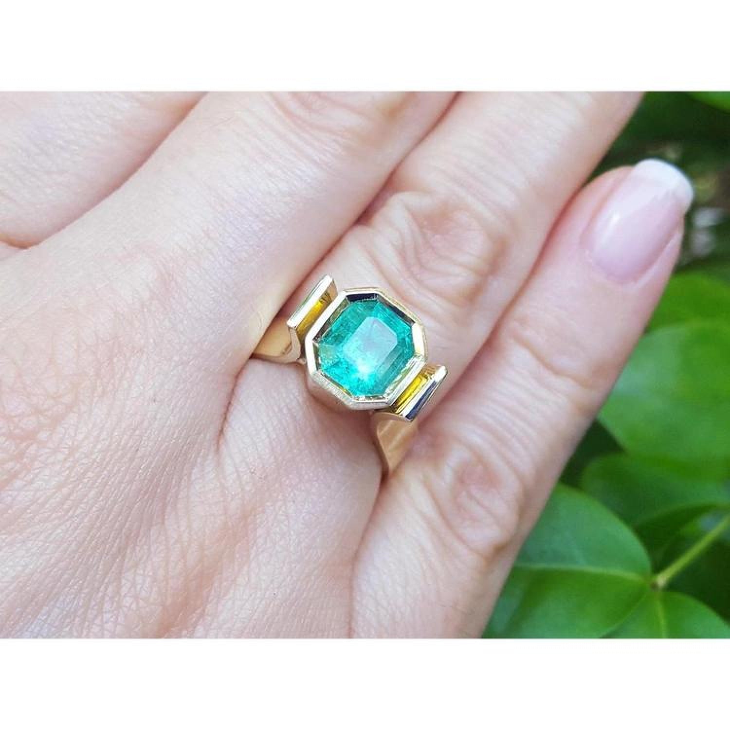 2.14 ct. rectangular emerald-cut Colombian emerald bezel set in a 14K yellow gold solitaire ring.
