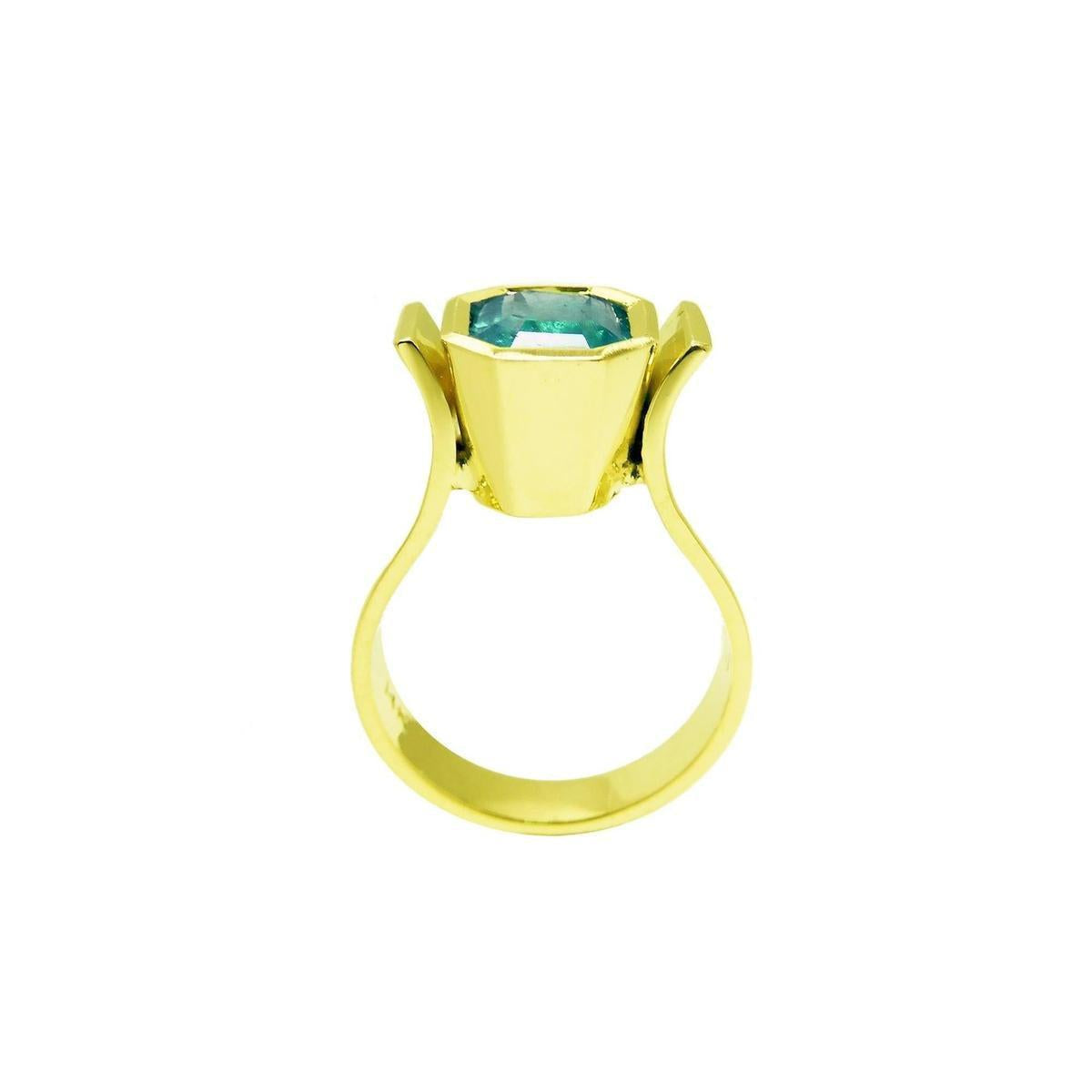 The lateral position of this 14k yellow gold emerald solitaire ring shows the bezel setting and band of the ring.