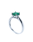 The half side profile view of a silver solitaire ring with a genuine emerald on a white background