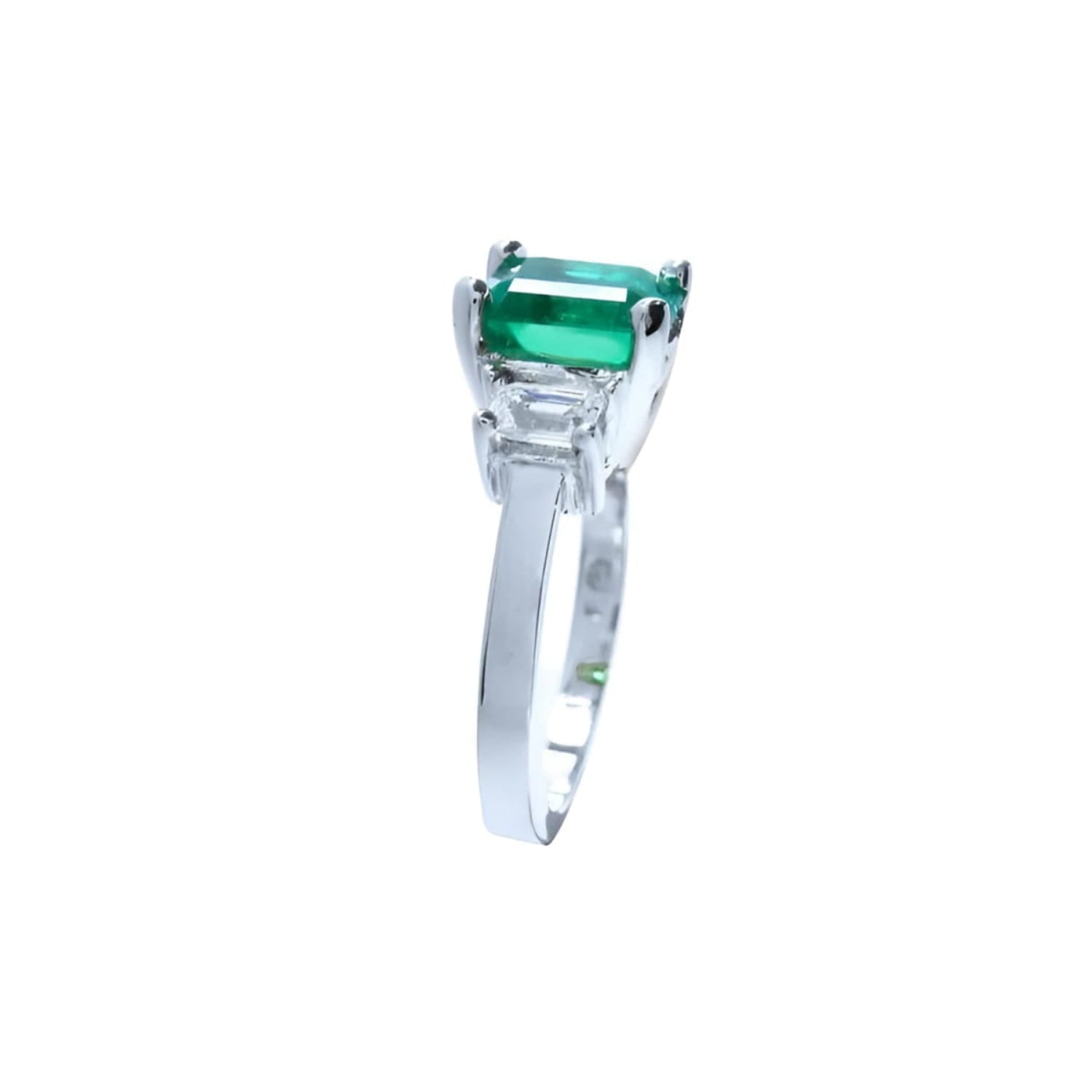 18K white gold three-stone ring with a rectangular emerald and two side emerald-cut diamonds.