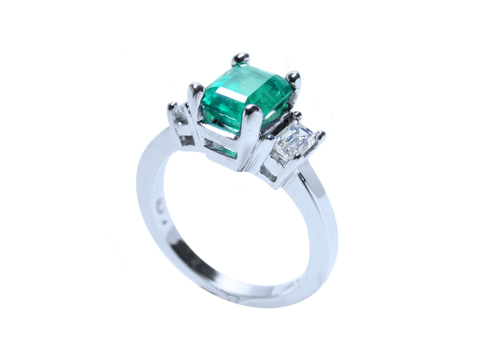 A 18k white gold emerald ring three stone on a half side profile view.