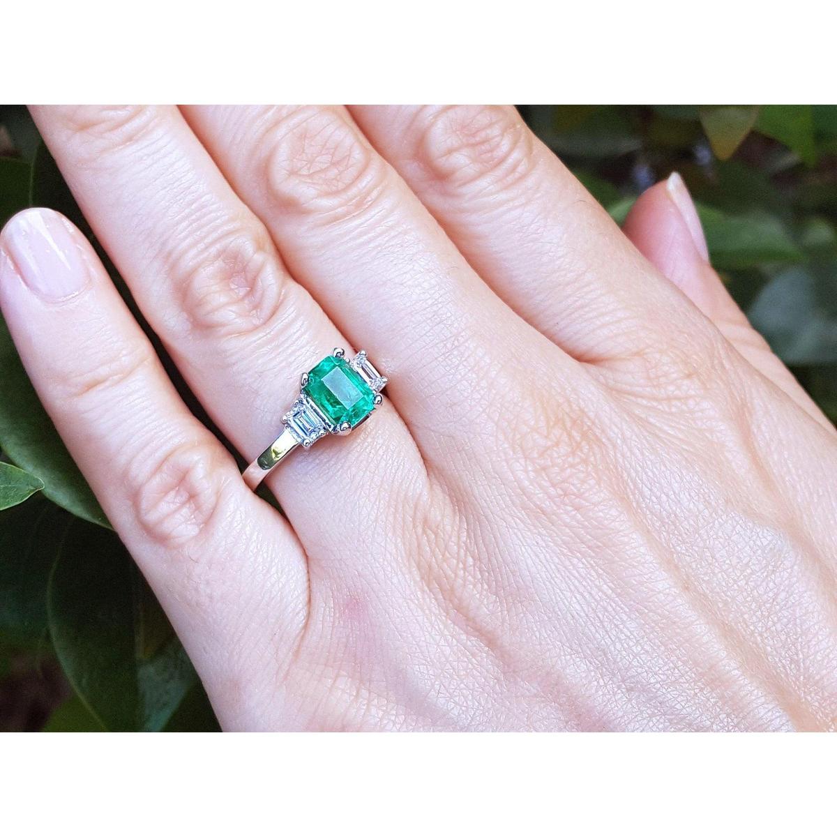Emerald ring on a hand with a green leafy background