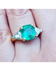 18k Gold emerald and trillion side diamonds ring on a hand.