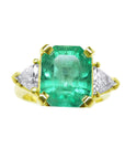 Three stone emerald and trillion cut side diamond ring, front position top view.