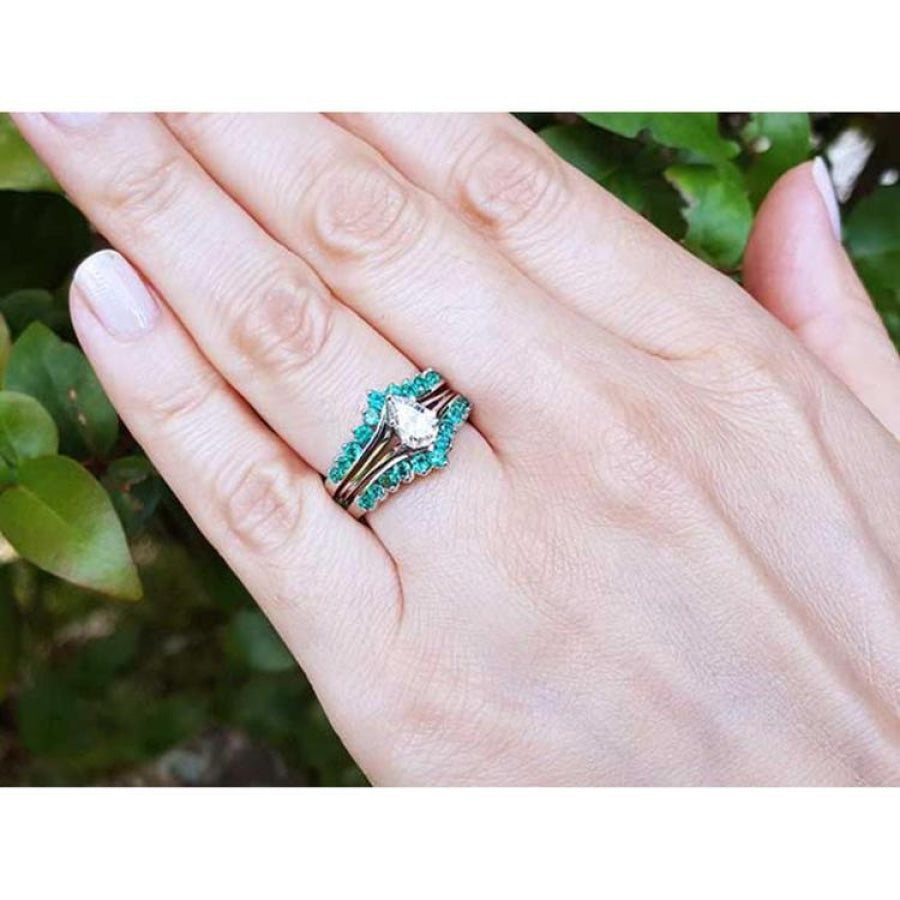 Hand wearing a 14k white gold emerald ring enhancer with 22 round cut Colombian emeralds, surrounding a solitaire ring.