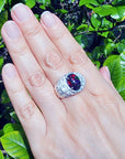 Hand wearing a silver ring for men with a colorful black opal against a green leafy background
