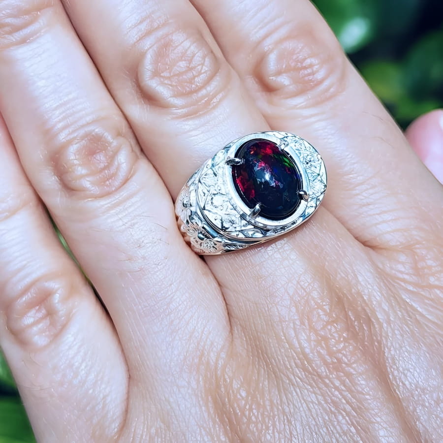 Men's sterling silver ring with a fiery red Ethiopian black opal, oval cabochon, and engraved band.