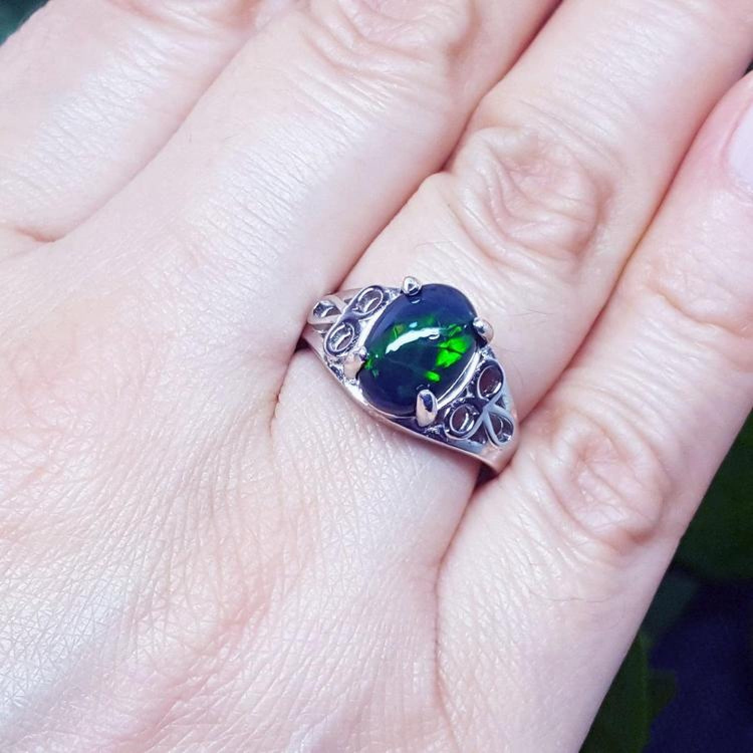 Sterling silver ring with a 2.15 ct oval black Ethiopian opal showing green-blue play of color, worn on a finger.