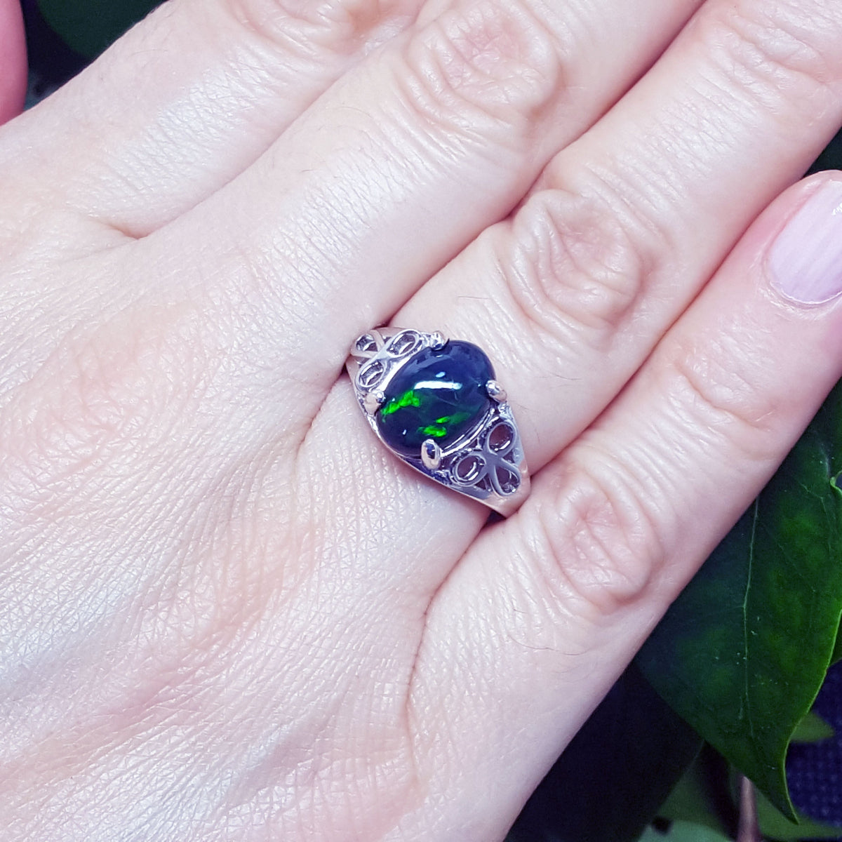 Ring with an opal stone on a hand, with a natural background