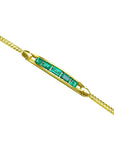 This far view of a gold bracelet with natural emeralds is on a white background.