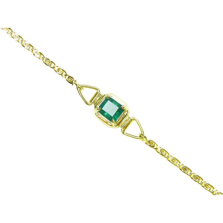Gold bracelet with a natural colombian emerald on a topside view.