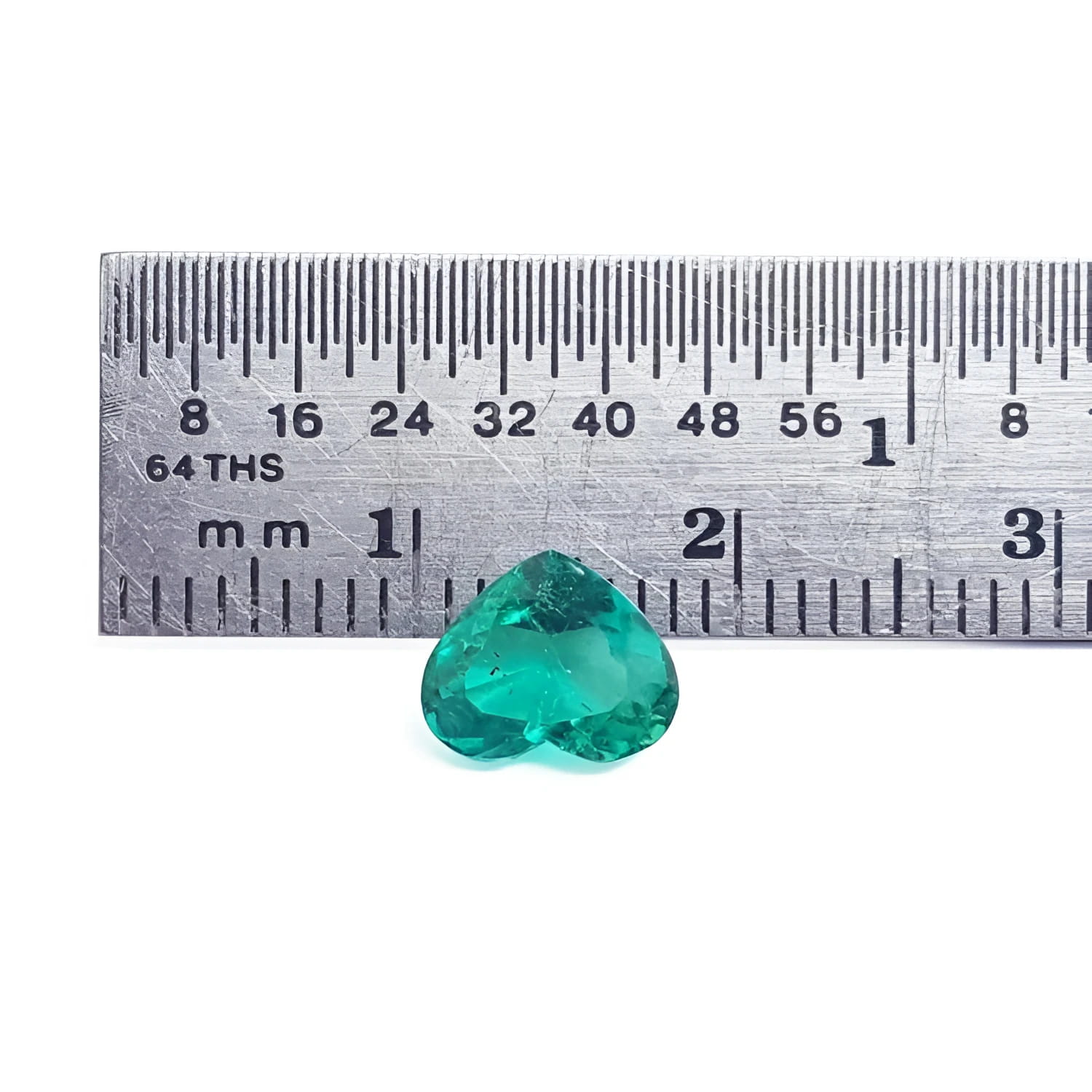 1.14 carat heart-cut Colombian emerald, rich bluish-green, shown with a ruler for scale.