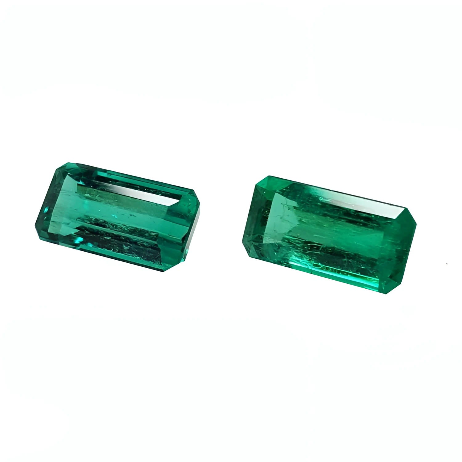 Two sparkling, emerald-cut natural emeralds with a medium deep bluish-green hue.