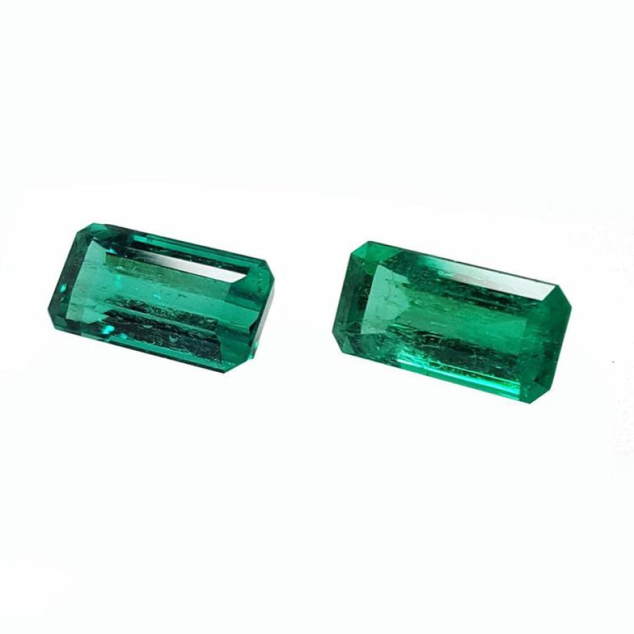Two sparkling, emerald-cut natural emeralds with a medium deep bluish-green hue.