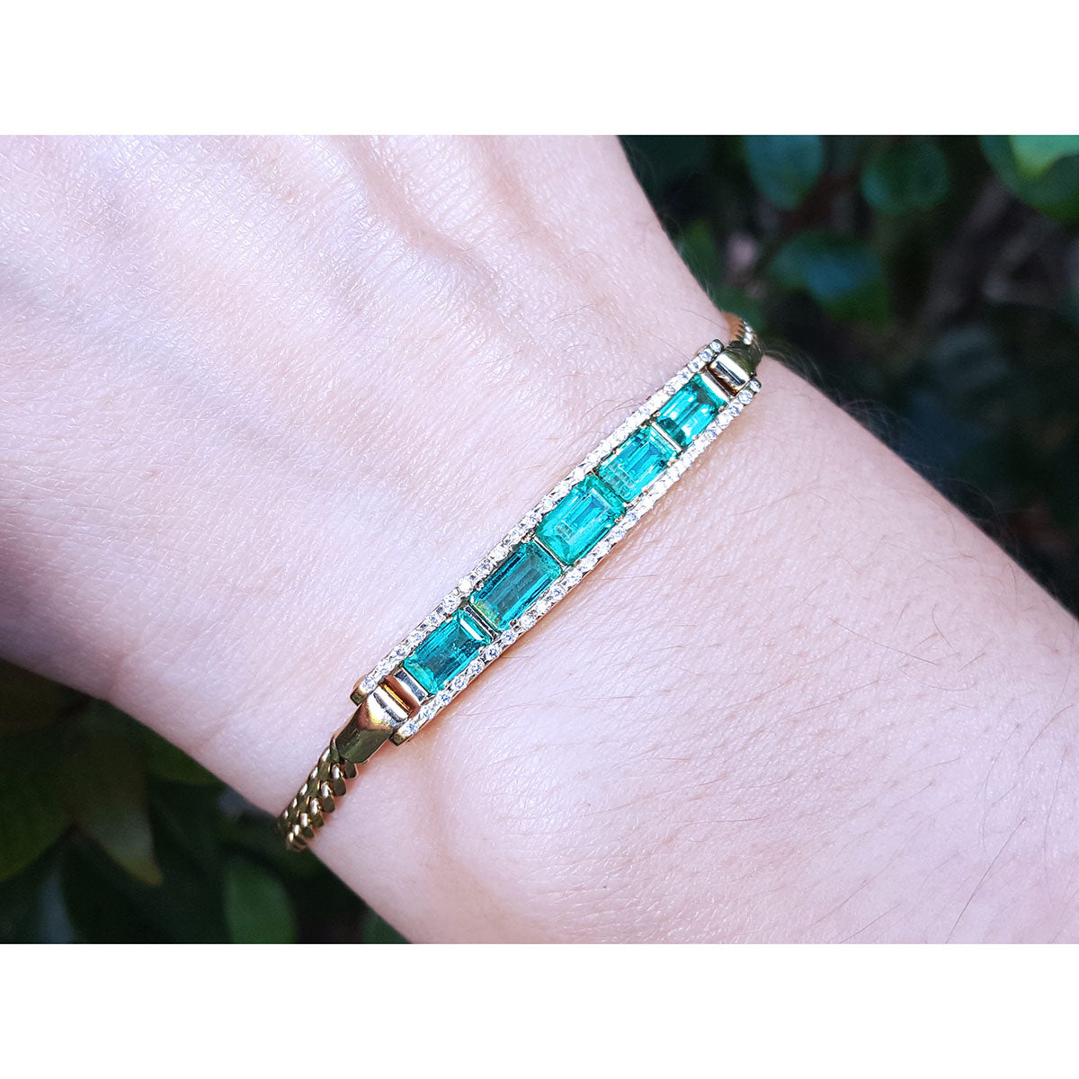 On a wrist a five natural Colombian emeralds bracelet for women handcrafted in 14k yellow gold.