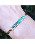 On a wrist a five natural Colombian emeralds bracelet for women handcrafted in 14k yellow gold.