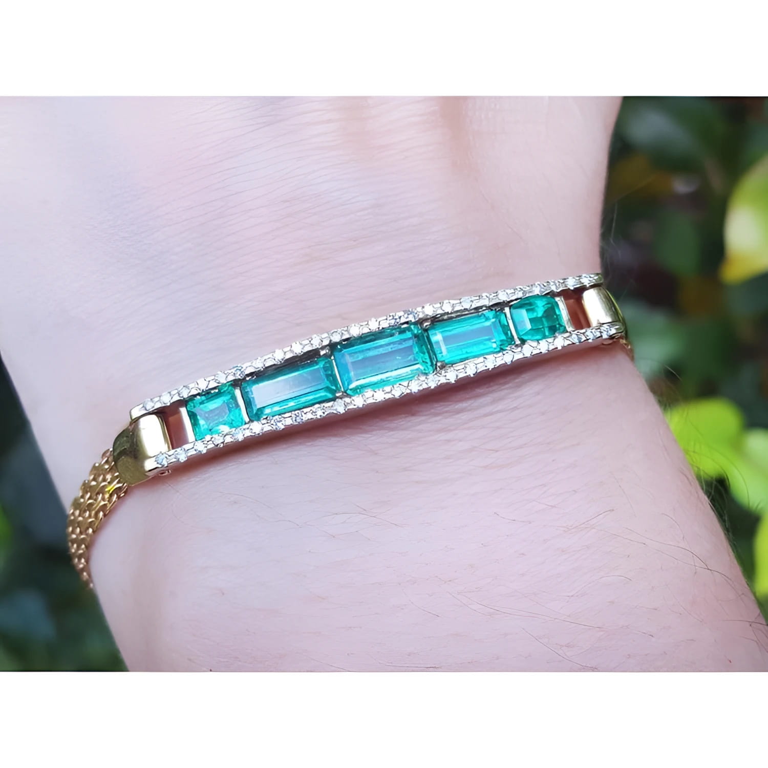 14K gold bracelet with five vibrant bluish-green emeralds and sparkling diamonds on a wrist.