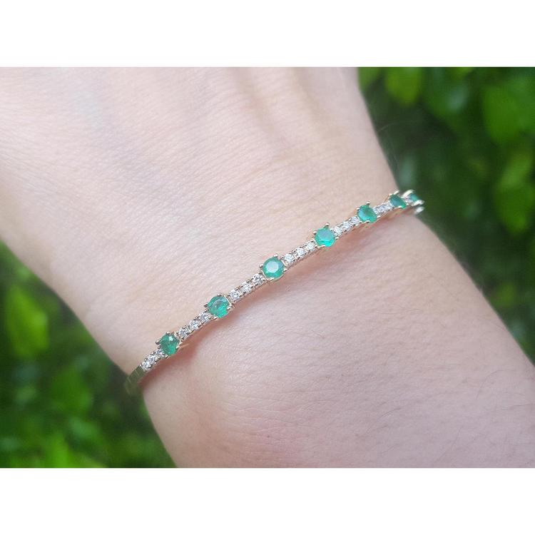 This natural colombian emerald bangle bracelet is flexible, and it is decorated with accent natural diamonds.