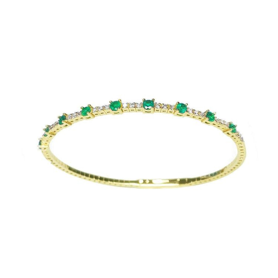 Flexible 14K yellow gold bangle with oval emeralds and accent diamonds.