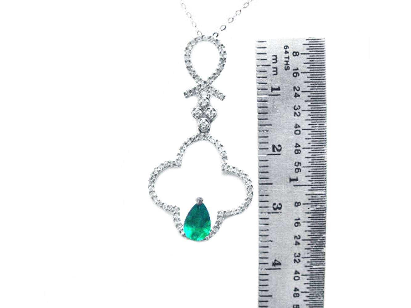 Necklace with a teardrop-shaped emerald pendant next to a ruler for scale on a white background