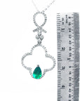 Necklace with a teardrop-shaped emerald pendant next to a ruler for scale on a white background