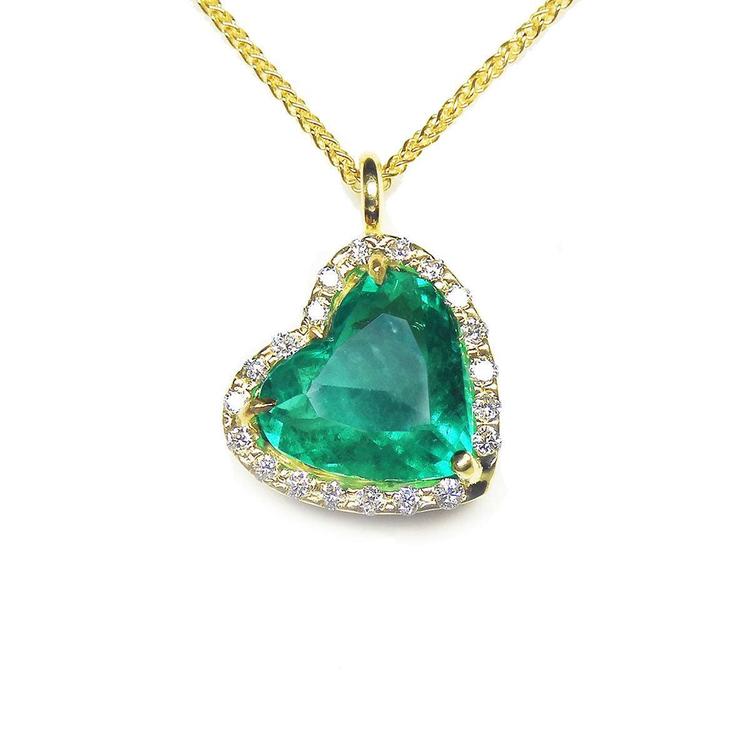 Gold necklace with a heart-shaped emerald pendant on a white background