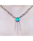 close frontal view of a kisses and hugs necklace with a natural emerald gemstone on a white background