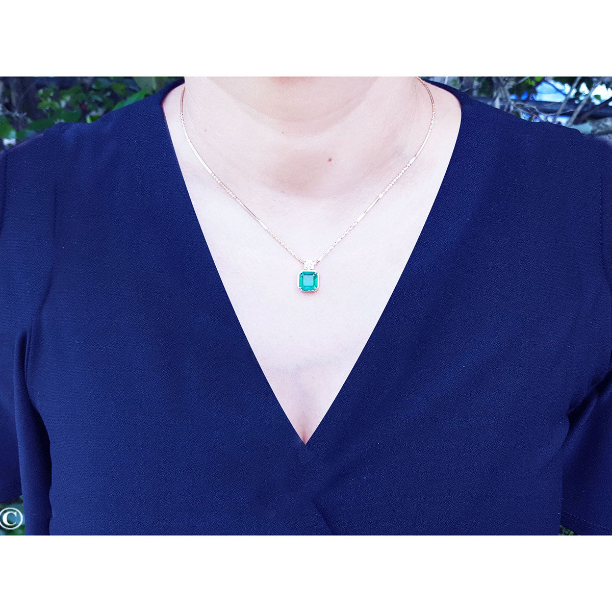 Front view of a Muzo Colombian emerald necklace yellow gold on a lady&#39;s collar