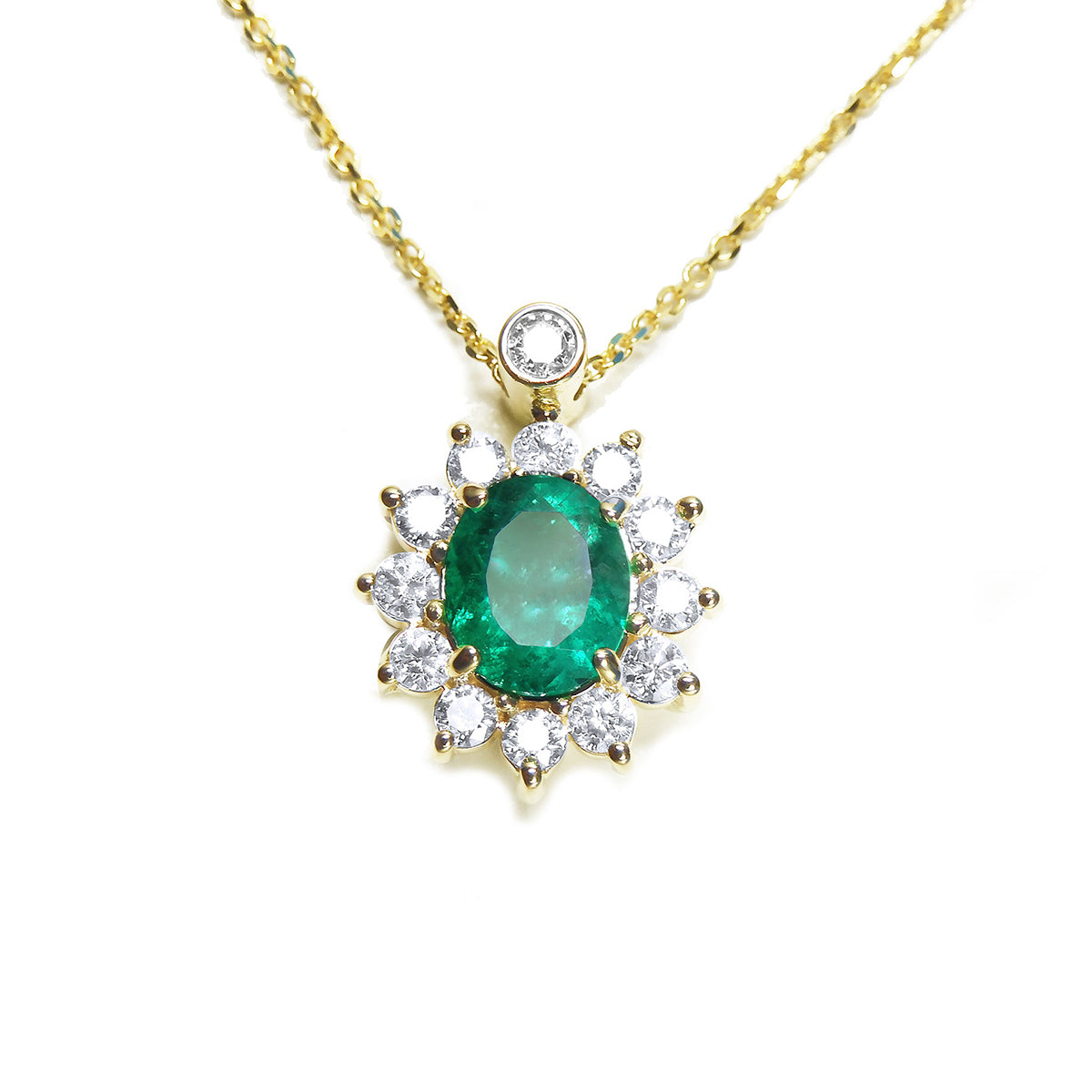 Front view of a gold necklace with an oval emerald in a halo diamond pendant on a white background