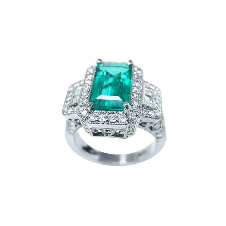Anillo de compromiso de oro blanco 18k con esmeralda colombiana rectangular verde y diamantes.
