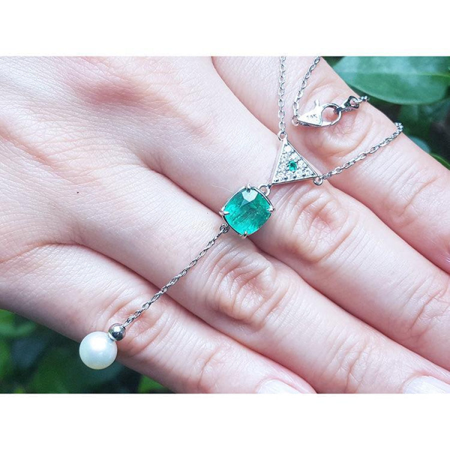 14K white gold necklace with a cushion-cut emerald, diamond triangle cluster, and dangling white pearl.