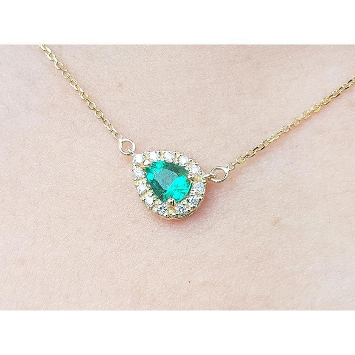 Vibrant pear-shaped emerald necklace with diamond halo on a 14K yellow gold chain.
