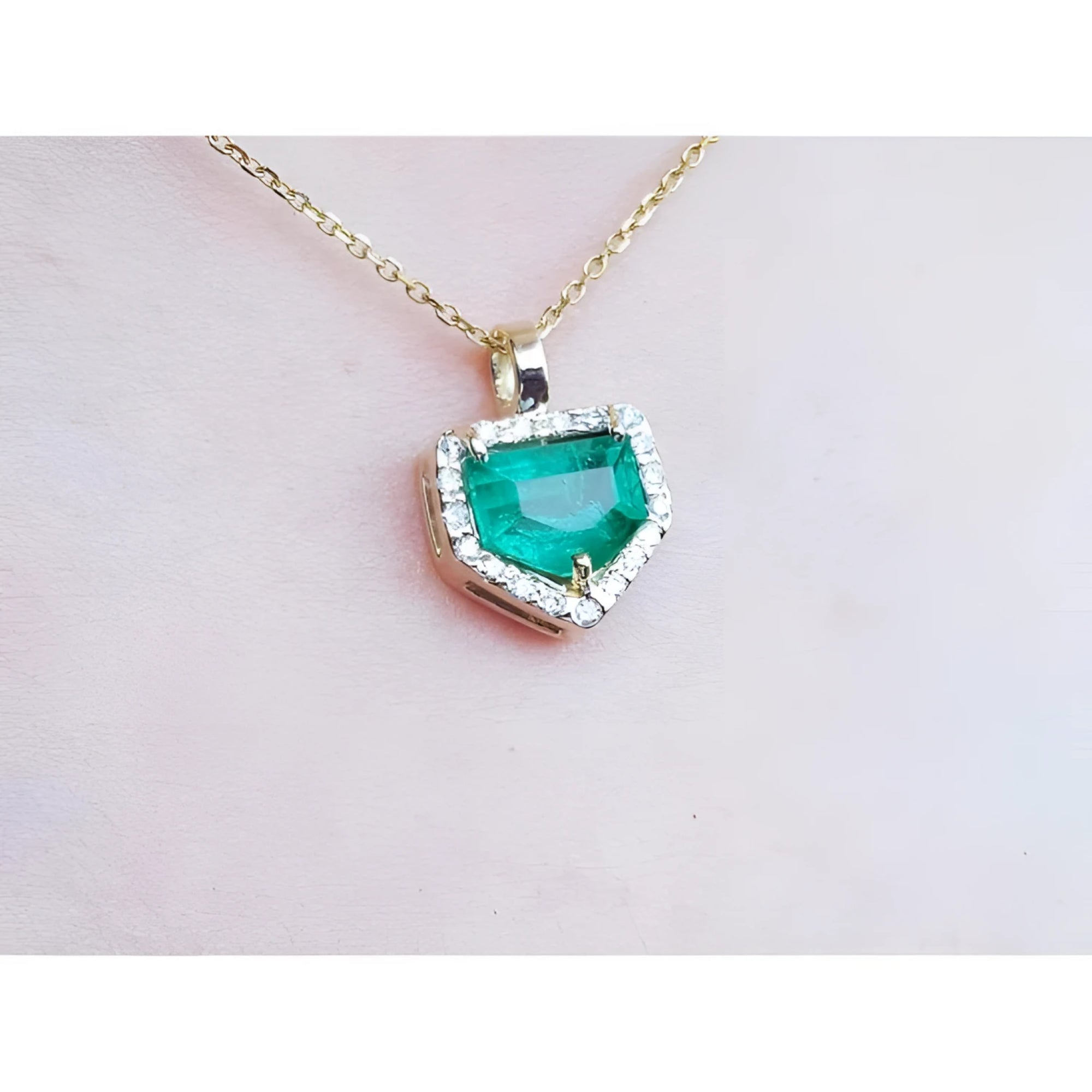 14K gold pendant with a vibrant green Colombian emerald and diamond halo.