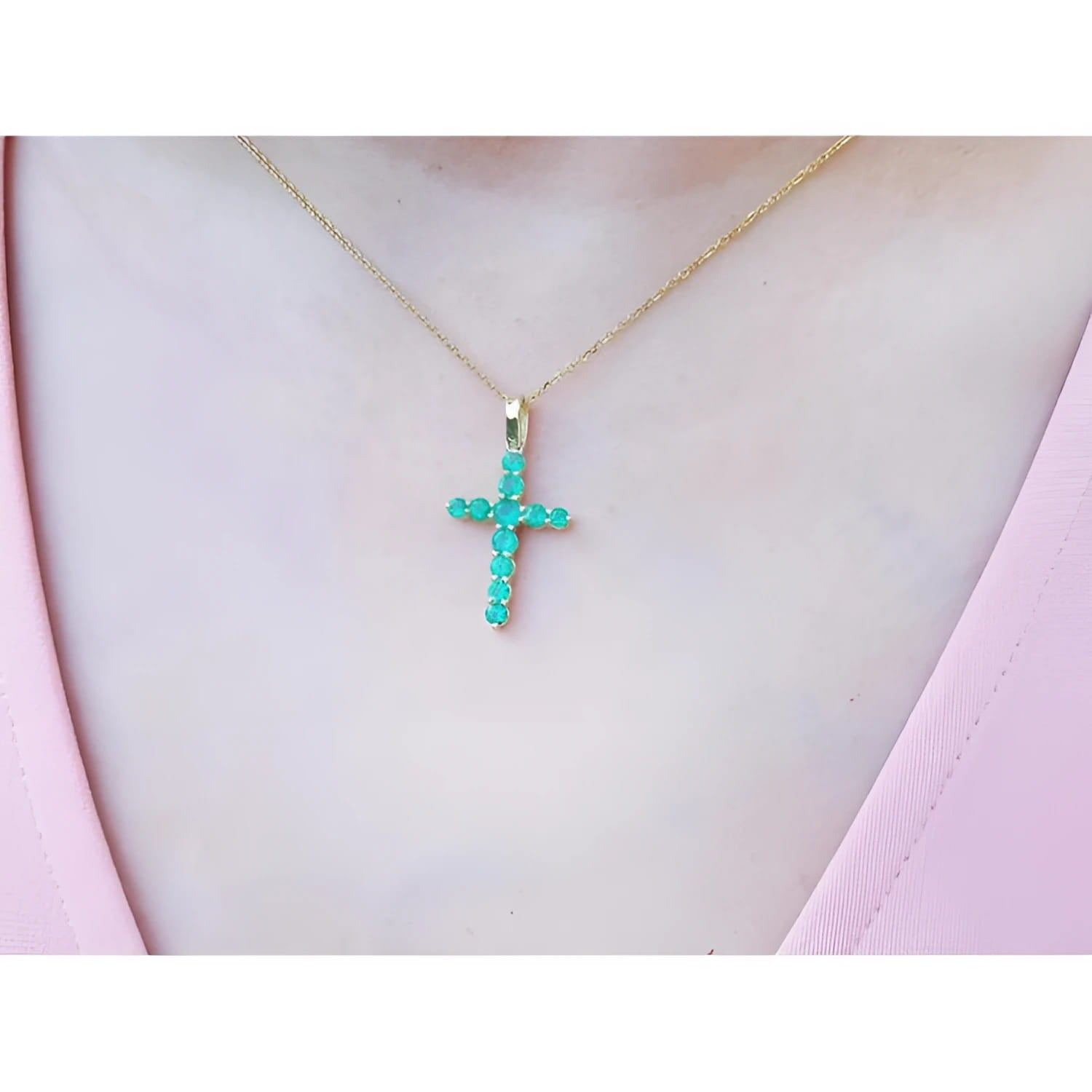 18K yellow gold cross pendant necklace with genuine emeralds on a woman's chest.