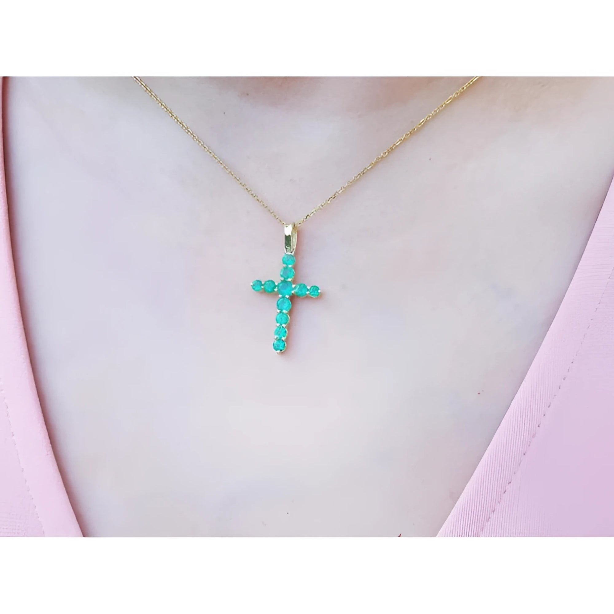 18K yellow gold cross pendant necklace with genuine emeralds on a woman's chest.